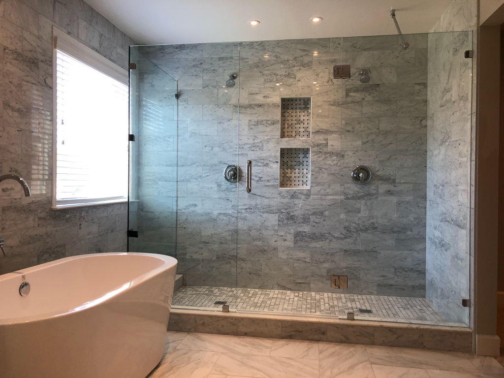 This enormous shower door is features a glass-to-glass door to maintain the frameless appearance.