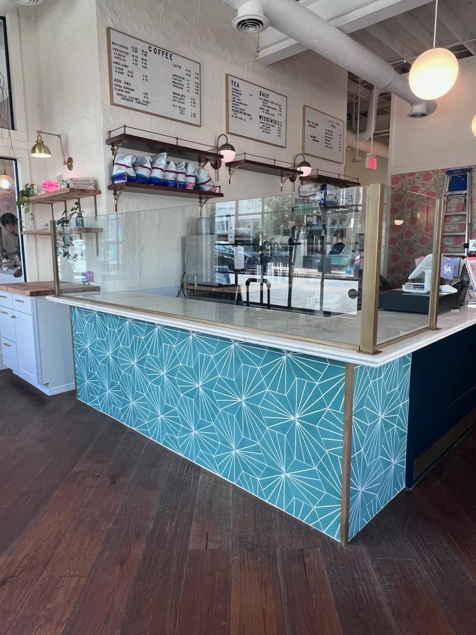 This sneeze guard for The Little Tart Bakery off of Georgia Ave is custom finished with a Spanish Gold powder coat and pencil polished glass for the most food safe, customized, sneeze guard application! These panels also maximize space for the bakery by providing enough room for three sheet pans of their delicious baked goods to lay just behind the glass enclosure.